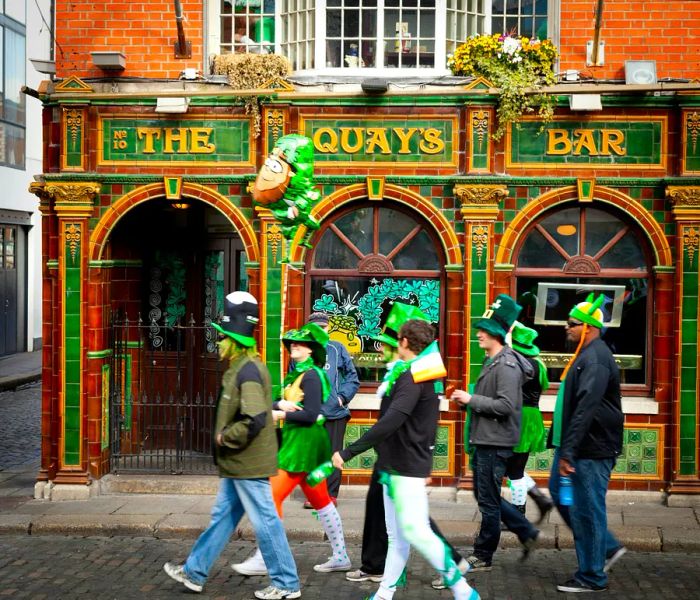 A group of revelers in costumes makes their way past a Dublin pub on St. Patrick's Day in the Republic of Ireland