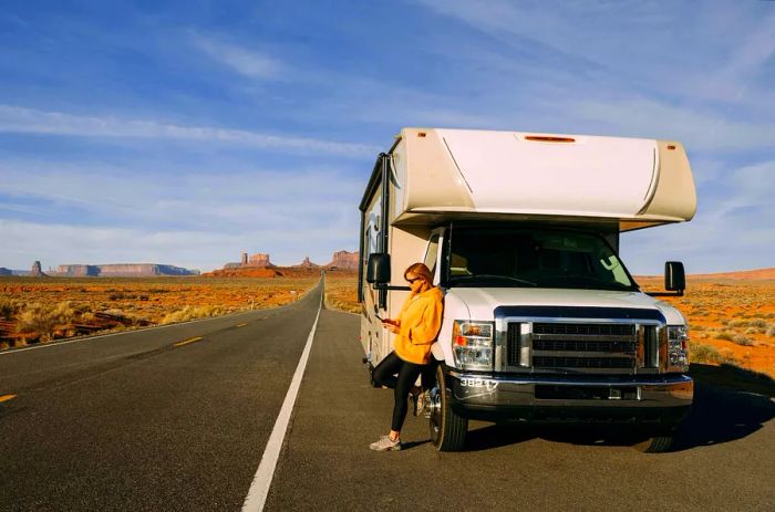 A woman stands outside her RV parked along the road in Monument Valley, Utah, USA