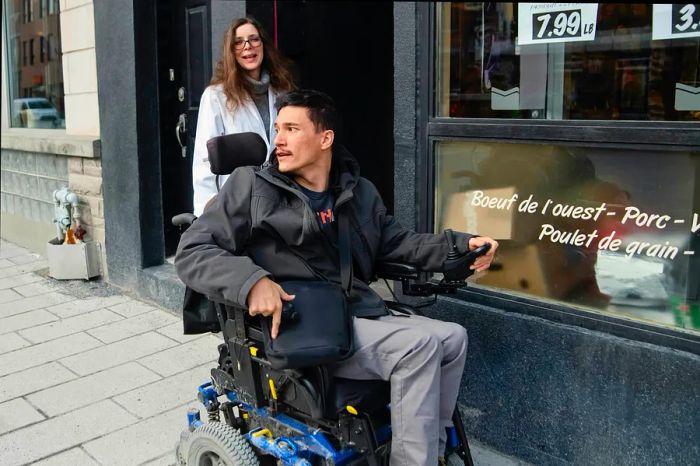 A young man using a motorized wheelchair exits a store in Montréal, Québec, Canada