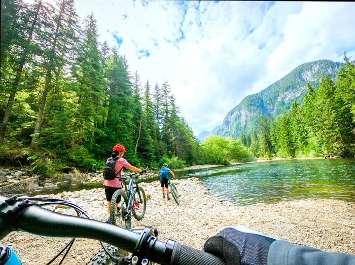 A family riding their bikes next to a rocky stream near the Seymour River in North Vancouver, British Columbia, Canada