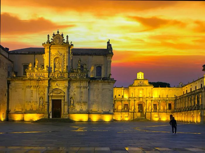 A stunning sunset casts a glow behind Lecce Cathedral as a person strolls through the plaza.