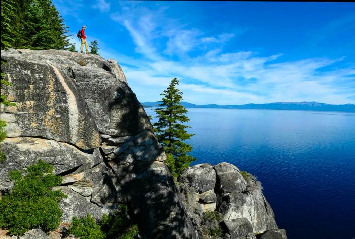 A hiker gazes out over picturesque lakeside views from a rocky outcrop