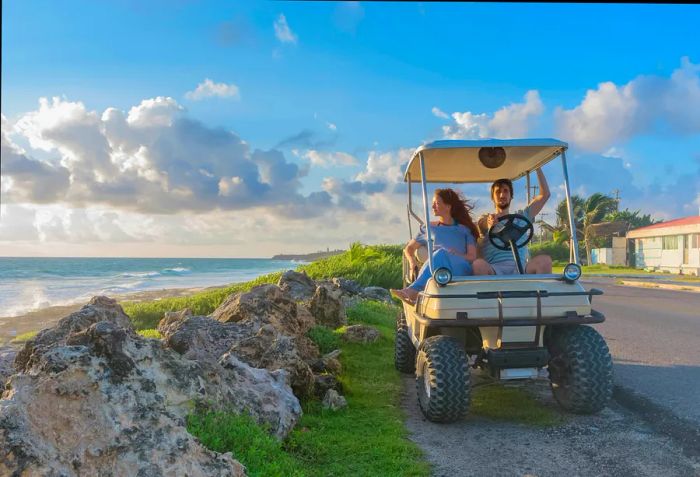 A young couple cruising in a golf cart along a tropical beach