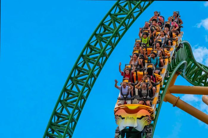 Thrill-seekers enjoying the exhilarating Cheetah Hunt rollercoaster against a backdrop of a light blue, cloudy sky.