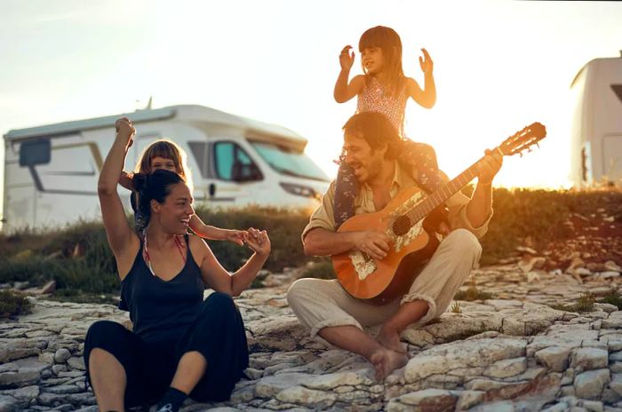 A family joyfully singing together on a Croatian beach with their camper van parked nearby.