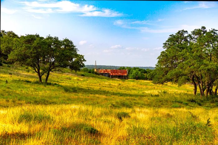 Rolling hills and a barn set against the blue skies of Texas Hill Country