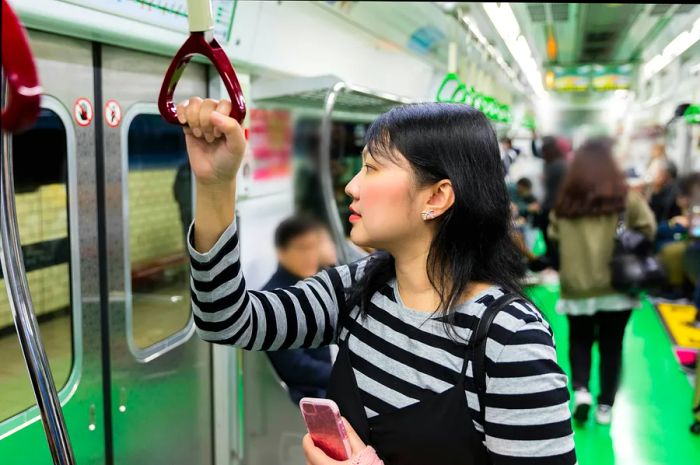 A woman grips the strap while standing on the Seoul subway