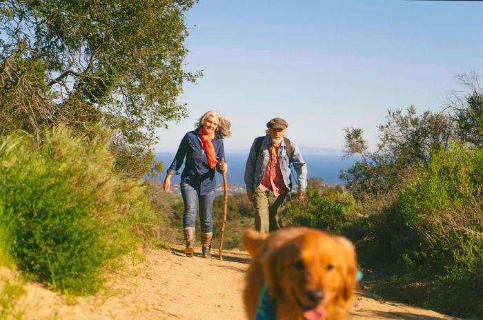 A middle-aged couple strolls along Solstice Canyon in LA's Santa Monica Mountains with their Labrador retriever.