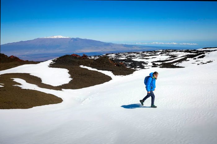 A woman hikes through snow at Hawaii Volcano National Park, Hawai‘i (the Big Island), Hawaii, USA