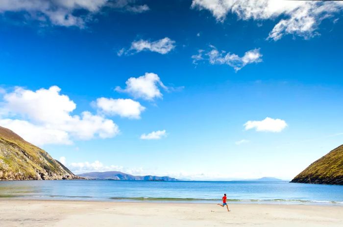 A child dashes joyfully along the shore at Keem Bay