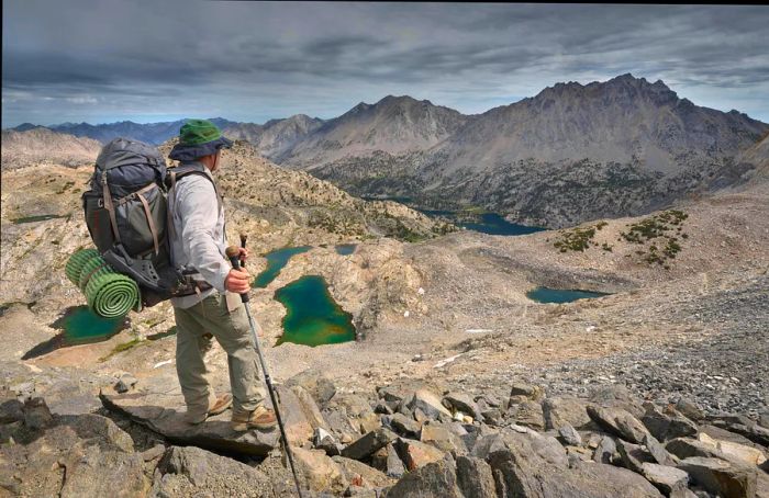 A male hiker standing atop the rocks at Glen Pass, Kings Canyon National Park, California, USA