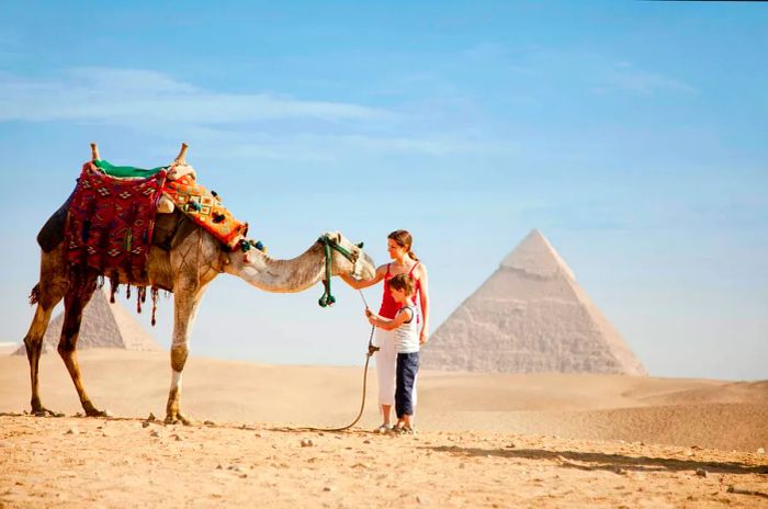 A mother and son enjoy a camel ride at the Pyramids of Giza, Egypt