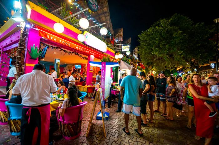 People waiting at the entrance of a restaurant during the bustling dinner rush on 5th Avenue, the shopping hub of Playa del Carmen, Cancún