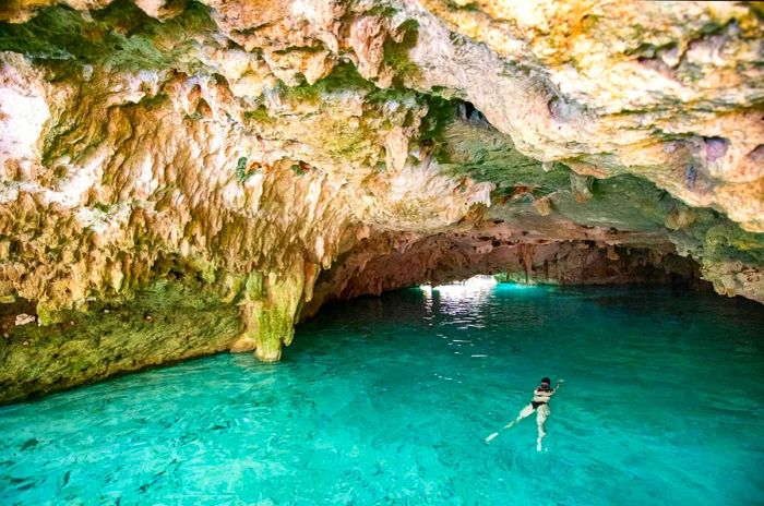 Woman swimming in freshwater within a cave