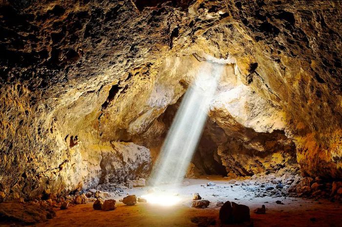 A beam of light illuminates a lava tube in Mojave National Preserve, showcasing the dramatic geological forces that shaped this part of California.