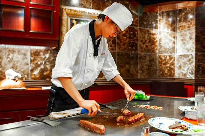 A young chef skillfully preparing wagyū (beef) at a restaurant in Kōbe, Japan