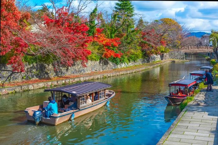 A serene boat gliding through Hachiman-bori canal in autumn, Ōmihachiman, Japan