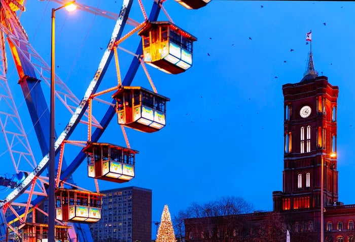 A Ferris wheel and the Town Hall create a magical scene at the nighttime Christmas Market in Berlin during winter.