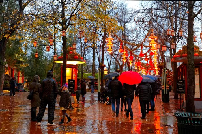 Visitors stroll through Tivoli Gardens on a rainy day in Copenhagen