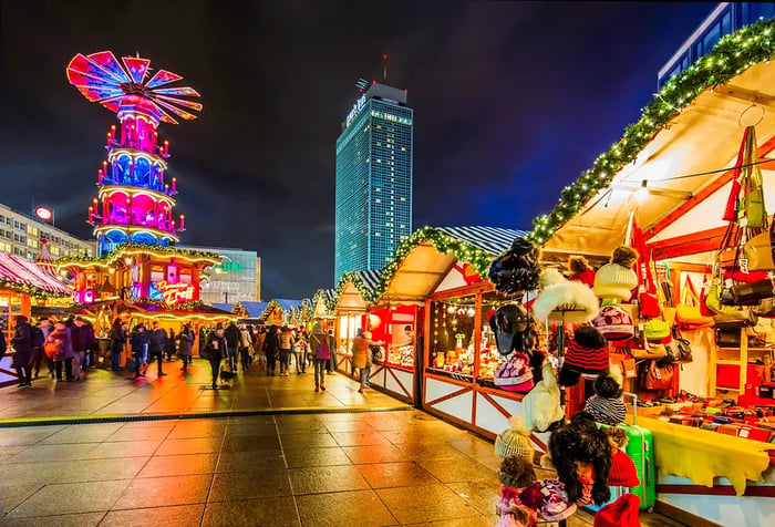 The Alexanderplatz Christmas Market in Berlin features a stunning tall hotel illuminated in the background.