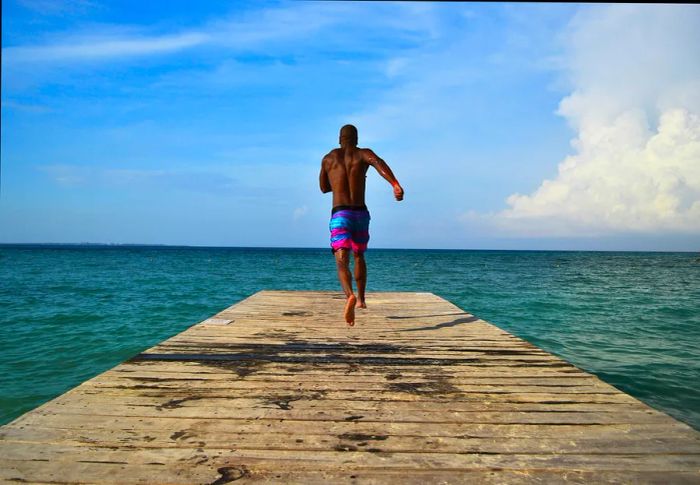 A man races down a dock to leap into the clear Caribbean waters of Cancún