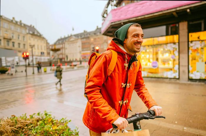 A cheerful man rides an electric scooter across a bustling city square