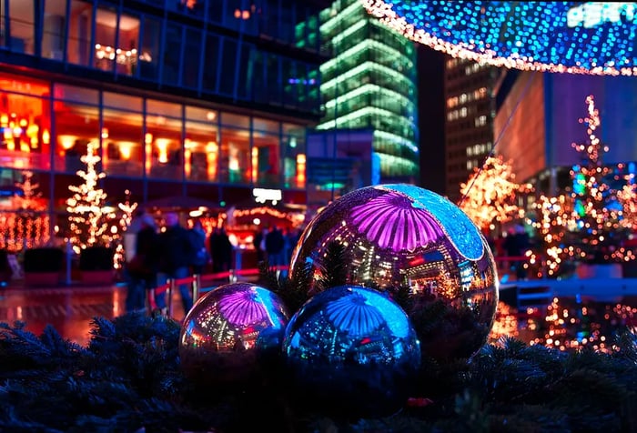 Christmas market adorned with lights at Berlin's Sony Center, mirrored in shiny metal baubles