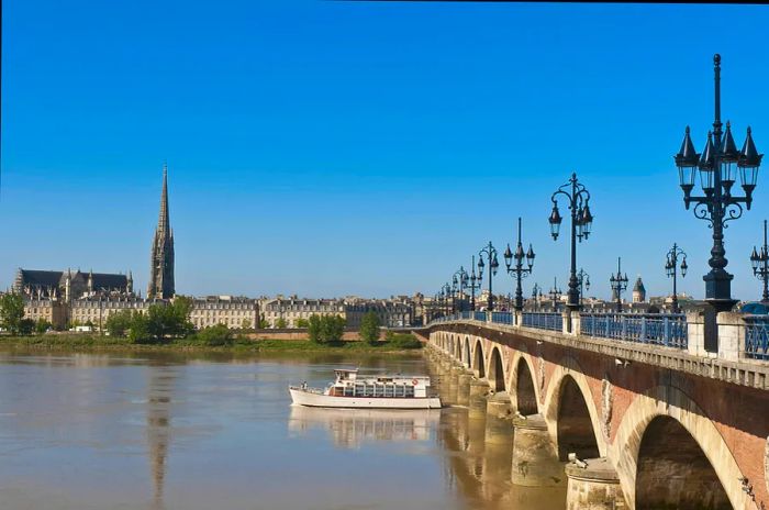 A boat glides beneath the St-Pierre bridge on the Garonne River, Bordeaux, France