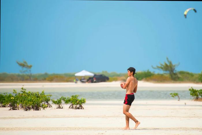 A young man tosses a football on the pristine sands of Isla Blanca, Cancún.