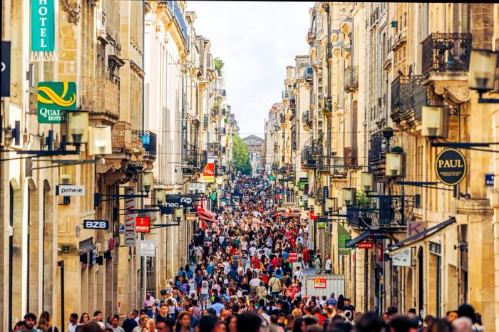 A bustling crowd fills a pedestrian shopping street in Bordeaux, Aquitaine, France