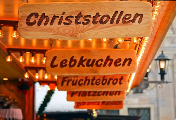 Wooden signs in German, illuminated by strings of light bulbs.