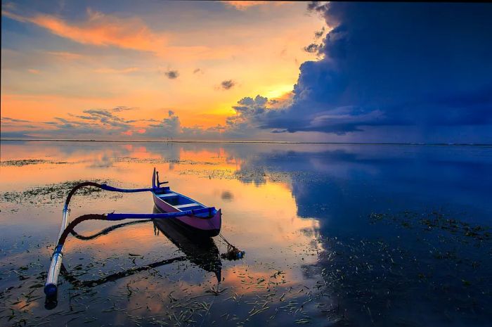 Dramatic dark clouds loom over the sea, contrasting with brighter areas nearby. A small rowboat rests on the beach in the foreground.