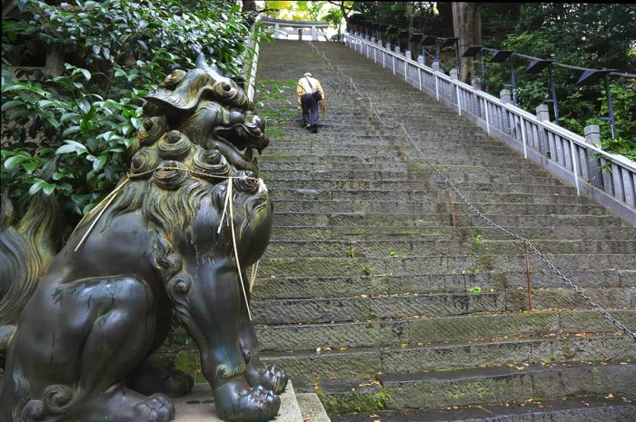 A man ascends a long series of concrete steps that lead up to the gateway of Atago Shrine, located near Kyoto.