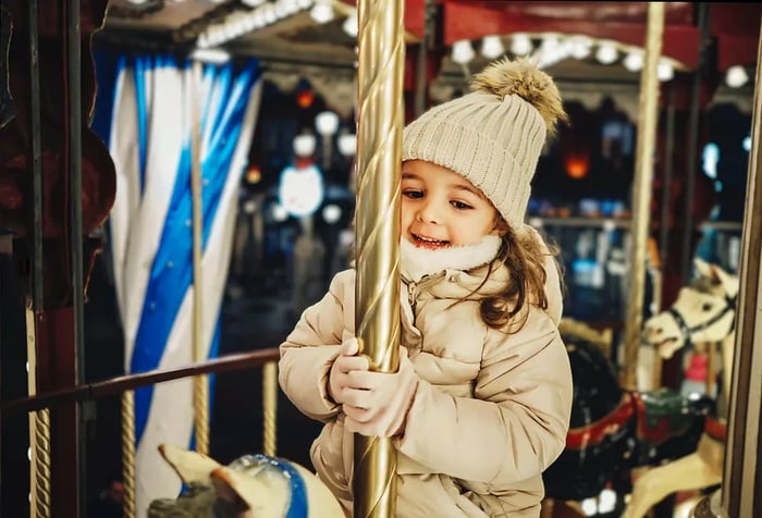 A joyful little girl enjoys a ride on a carousel horse.