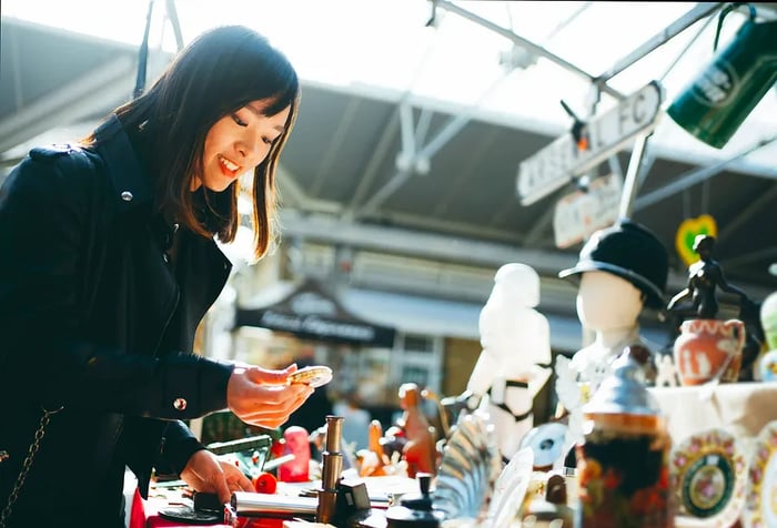 A young woman exploring a display of items at a market.