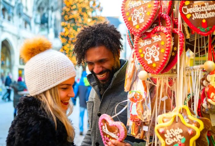 A joyful couple gazes at a heart-shaped Christmas keepsake, beaming with happiness.