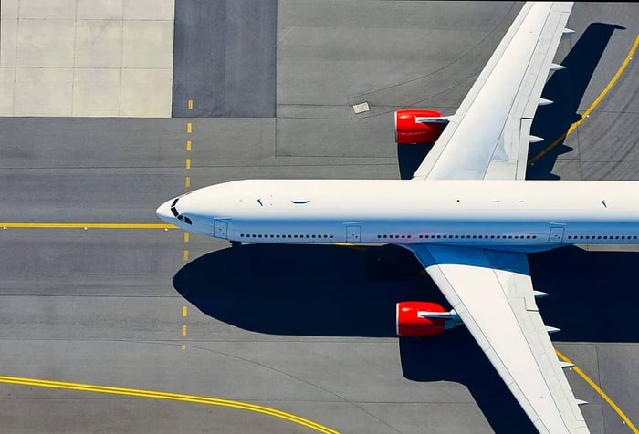 A white aircraft moves along a runway marked with yellow stripe indicators.