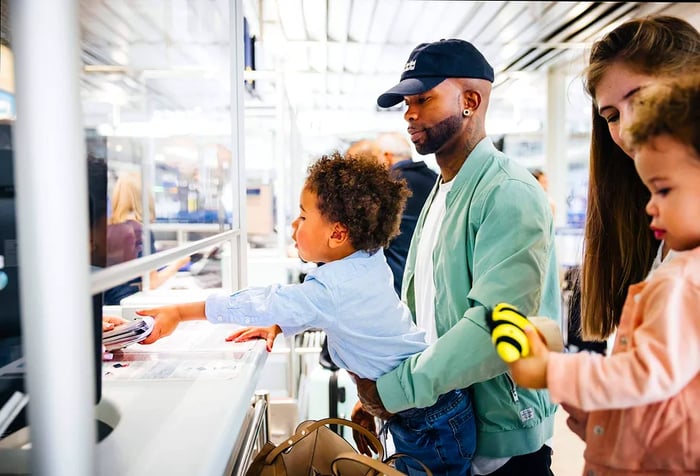 a man and woman along with their two children at the airport check-in receiving their passports