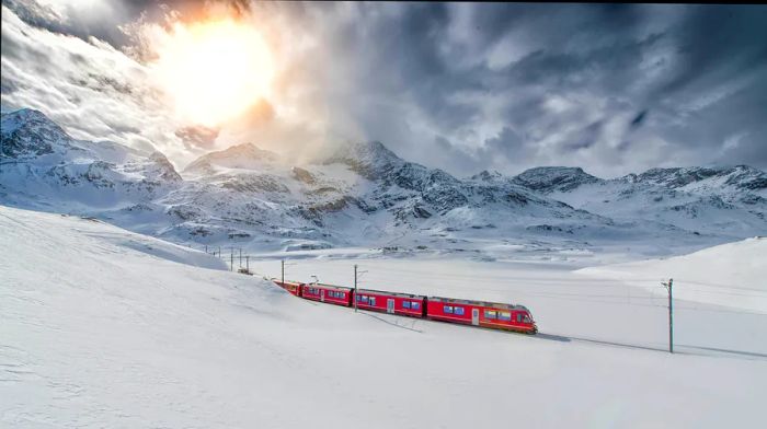 A Bernina Express train makes its way through a picturesque, snow-blanketed mountain range.