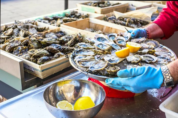 A platter of freshly opened oysters on ice, garnished with lemon, showcased on a street in Bordeaux.