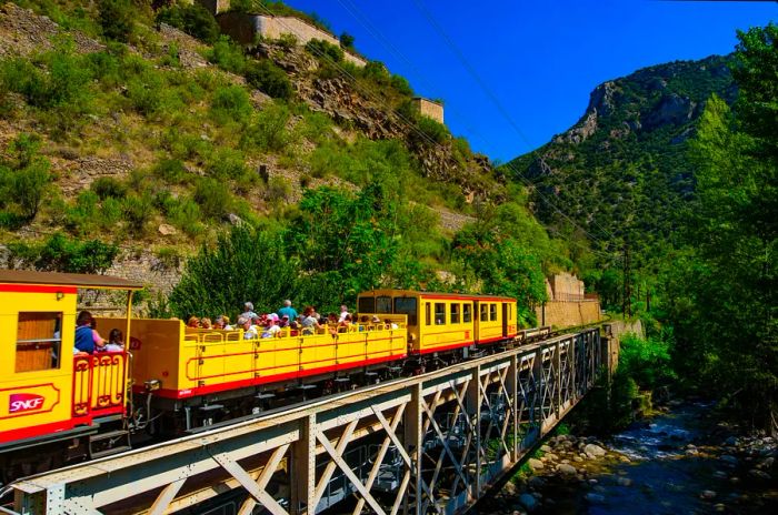 The Little Yellow Train (Le Petit Train Jaune) making its way through Villefranche-de-Conflent, France.