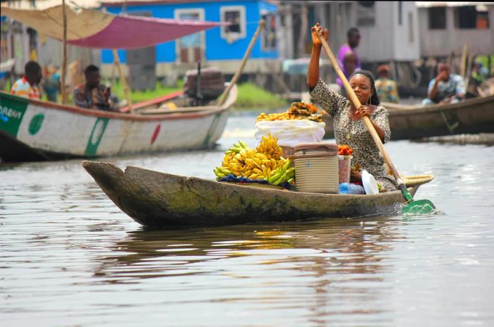 A woman paddles her canoe across Lake Nokoué from Ganvié, Benin