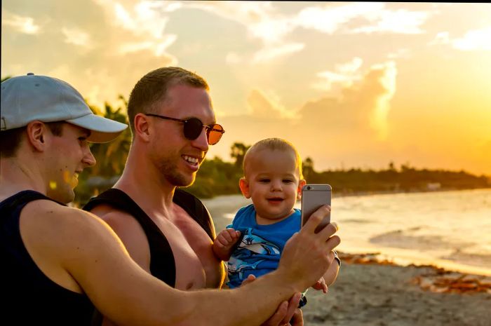 Two dads snap a selfie with their baby on the beach in Varadero, Cuba