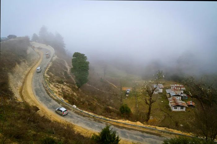 A twisting road leading to Dochu La Pass on a foggy day, Bhutan