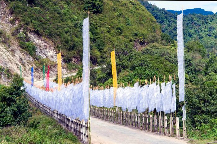 Buddhist prayer flags fluttering on a road bridge near Trashigang, Bhutan