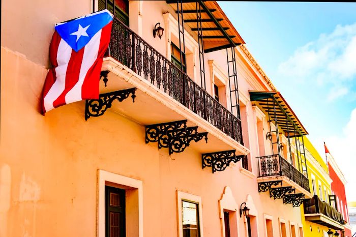 Vibrant house facades line a street in Old San Juan, Puerto Rico, with a Puerto Rican flag proudly displayed from one of the balconies.