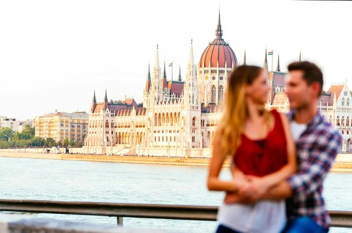 A young couple embraces in the heart of Budapest City, with a soft focus on the background.