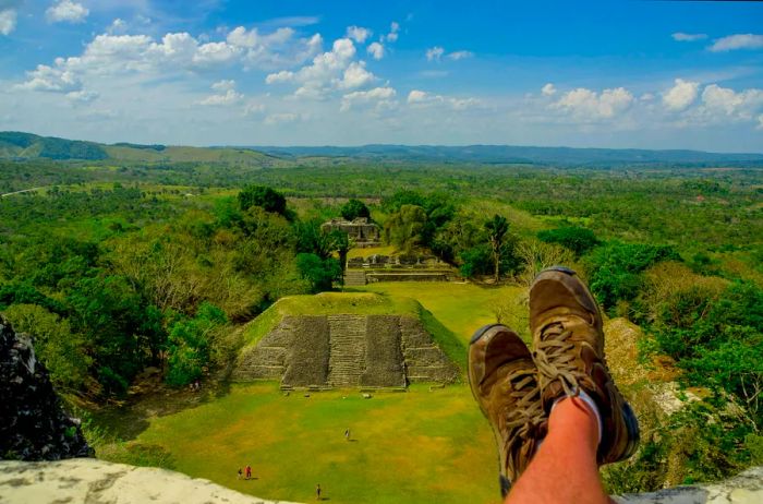 A pair of hiking boots rests at a viewpoint overlooking an ancient city hidden in the jungle