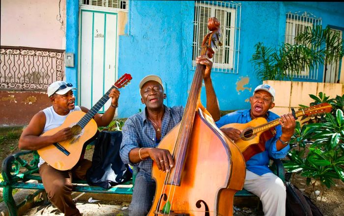 Three musicians enjoying a jam session on a bench in Santiago de Cuba