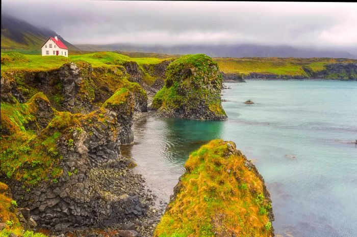 A charming white house perched by the volcanic coastal cliffs of Arnarstapi in Iceland